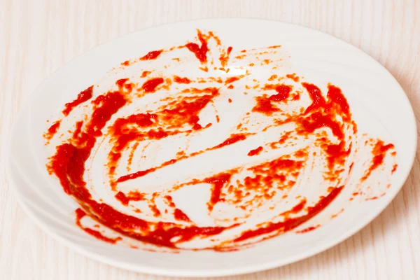 Placa sucia sobre la mesa. Salsa de tomate untada en un plato . — Foto de Stock