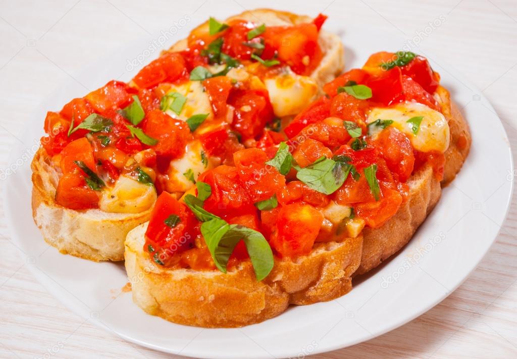 Italian tomato bruschetta with chopped vegetables, herbs, cheese and oil on grilled or toasted crusty ciabatta bread