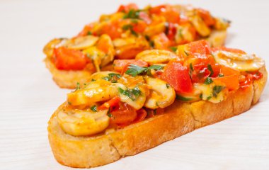 Doğranmış sebzeler, otlar, peynir ve tost huysuz ciabatta ekmeği üzerinde mantar domates bruschetta
