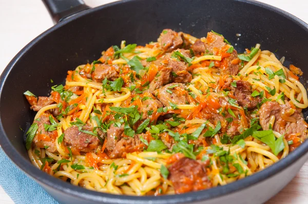 Шматочки м'яса та овочів з спагетті на сковороді — стокове фото