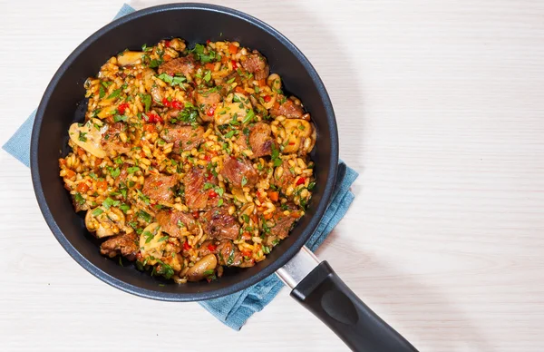 Rice with meat, vegetables and mushrooms in a frying pan — Stock Photo, Image