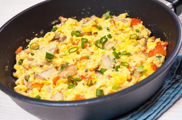 Huevos revueltos con setas y verduras en una sartén —  Fotos de Stock