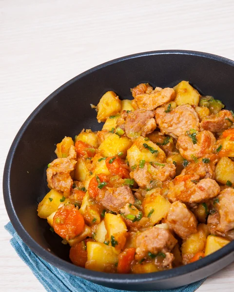 Gestoofde vlees met aardappelen, ajuin en wortel in een koekenpan — Stockfoto