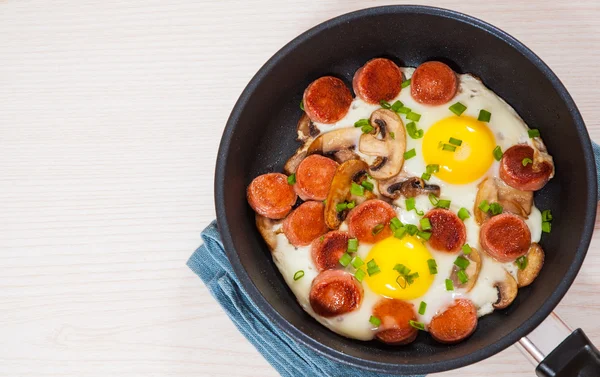 Spiegeleier mit Pilzen und Wurst in der Pfanne — Stockfoto