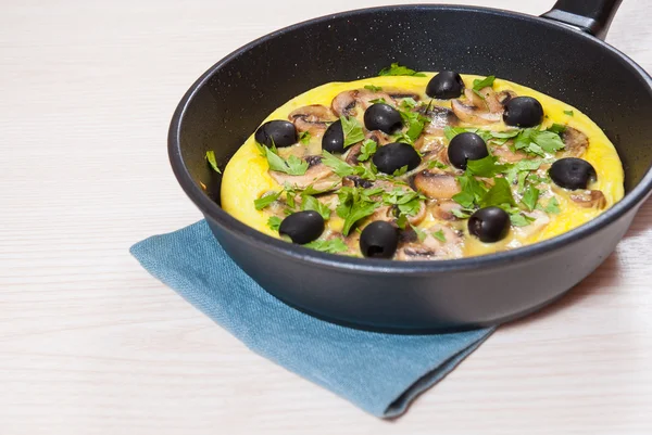 Omelet with mushrooms, and olives in a frying pan — Stock Photo, Image