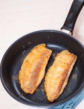 Fried fish fillet in a frying pan clipart