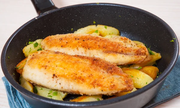 Filete de pescado frito y patatas en una sartén — Foto de Stock