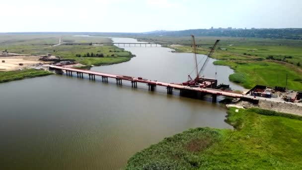 Luchtfoto van de bouw van een brug over de rivier. — Stockvideo