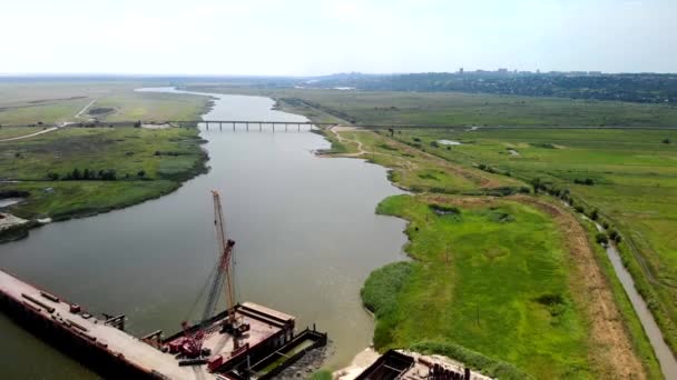 Luchtfoto van de bouw van een brug over de rivier. — Stockvideo