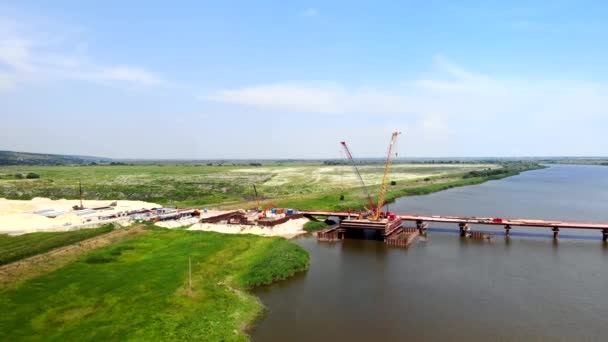 Luchtfoto van de bouw van een brug over de rivier. — Stockvideo