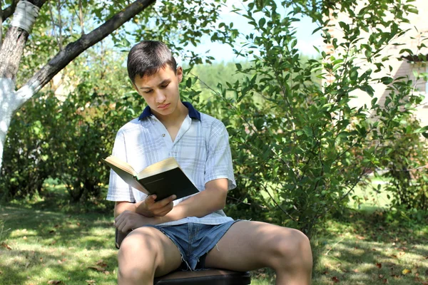 Boy outdoors reading book — Stock Photo, Image