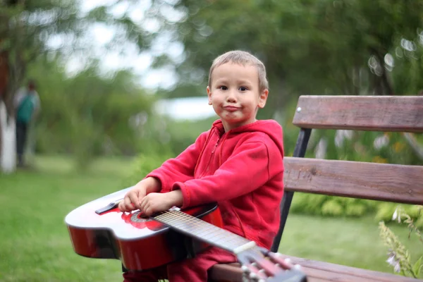 Маленький мальчик с гитарой на открытом воздухе — стоковое фото