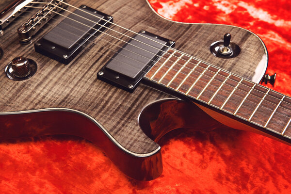 Black electric guitar on red velvet background
