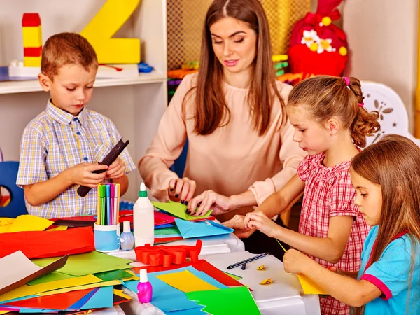 Kids holding colored paper on table in kindergarten . — Stock Photo, Image