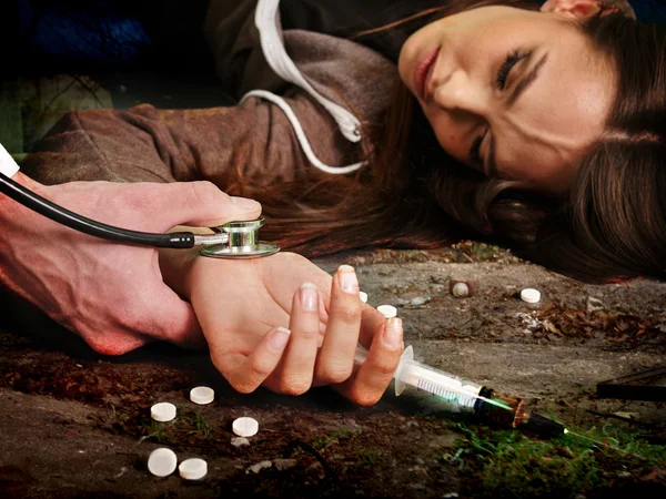 Mujer inconsciente adicta mantiene la jeringa y acostado en el suelo sucio . — Foto de Stock
