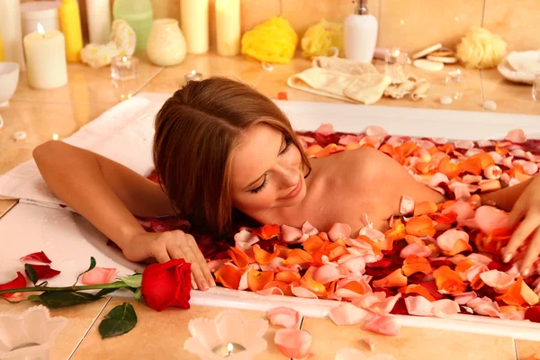 Chica tomando baño con pétalos de rosa en el baño . — Foto de Stock