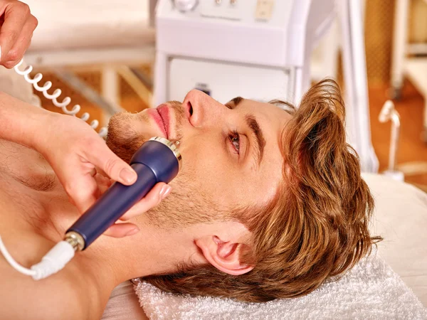 Young man receiving electric facial massage. — Stock Photo, Image