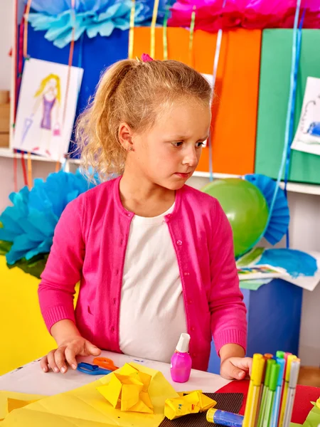 Kid holding colored paper on table in kindergarten . — Stock Photo, Image