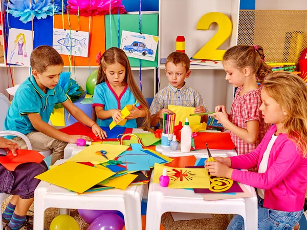 Kinderen houden gekleurd papier op tafel in de kleuterschool . — Stockfoto