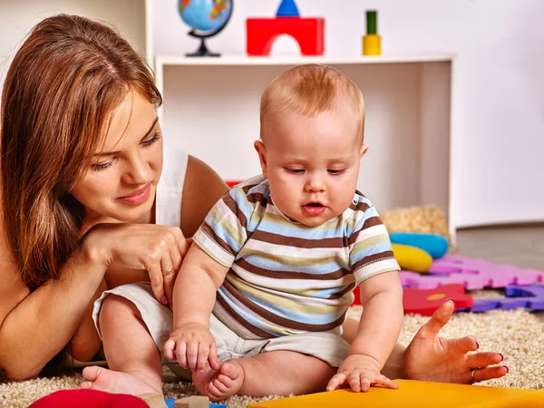 Kid with mother baby boy playing with puzzle toys on floor. — Stock Photo, Image