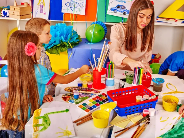 Niños con maestra pintando sobre papel en el jardín de infantes  . — Foto de Stock