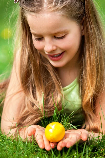 満足して女の子は屋外の緑の芝生での復活祭の卵を探してください。. — ストック写真