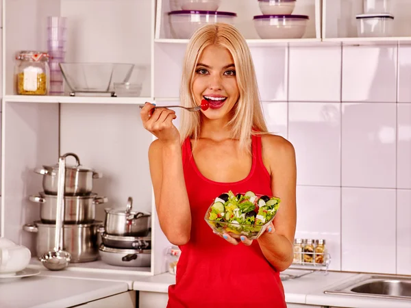 Frau isst Salat in Küche. — Stockfoto