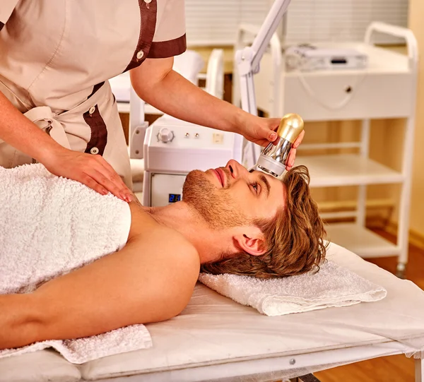 Young man receiving electric facial massage. — Stock Photo, Image