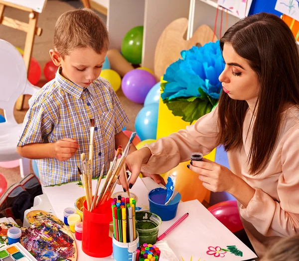 Kinderen met leraar vrouw schilderij op papier in de kleuterschool . — Stockfoto