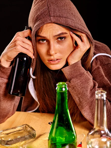 Dronken meisje houdt groen glazen fles wodka. — Stockfoto