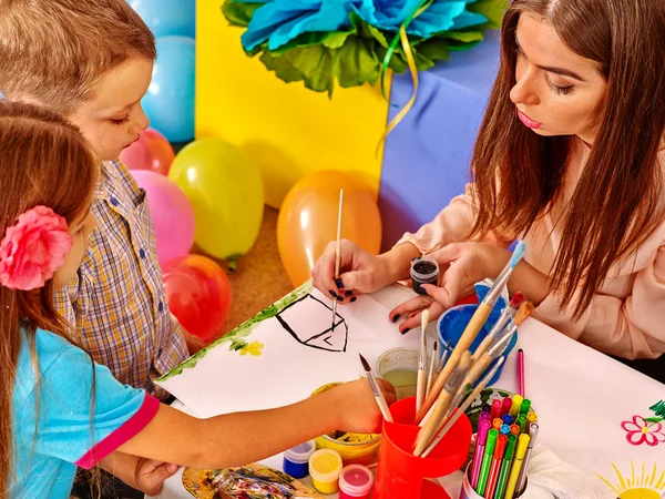 Enfants avec professeur femme peinture sur papier à la maternelle  . — Photo