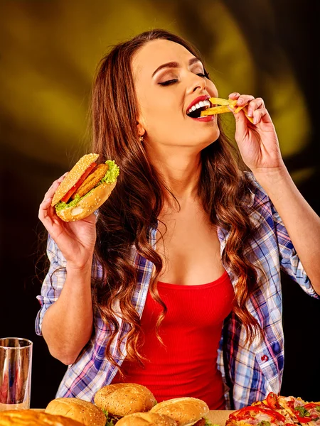 Menina comendo sanduíche grande e batatas fritas . — Fotografia de Stock