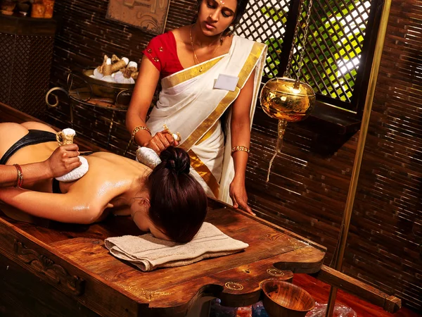 Mujer india haciendo masaje con una bolsa de arroz . — Foto de Stock