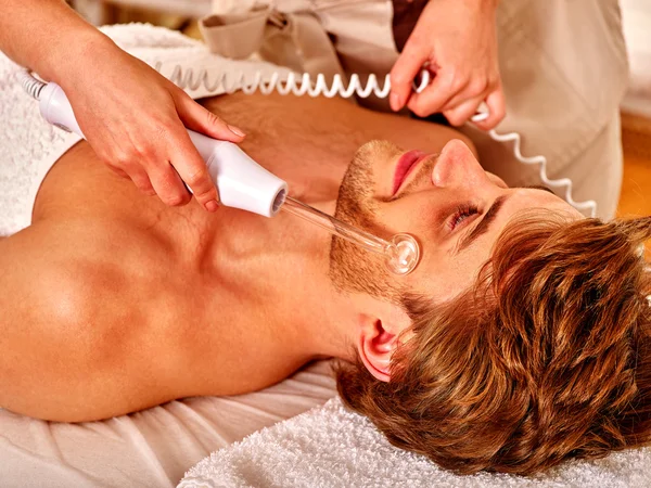 Young man receiving electric facial massage. — Stock Photo, Image