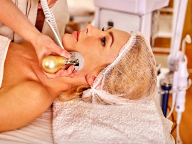 Elektrik yüz masajı alma rahat genç kadın.