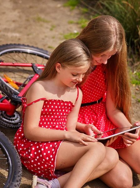 Vélos cycliste fille dans le parc. Enfants regarder comprimé pc . — Photo