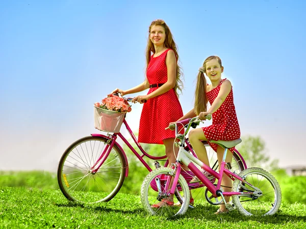 Meisje dragen rode polka stippen jurkje rijdt fiets in park. — Stockfoto