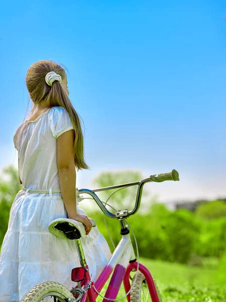 Barn tjej bär vit kjol Rider cykel i park. — Stockfoto