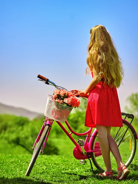 Girl wearing red polka dots dress rides bicycle into park. — Stock Photo, Image