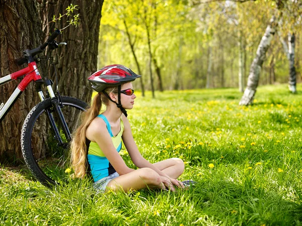 Vélos cycliste fille portant un casque ont un repos assis sous l'arbre . — Photo