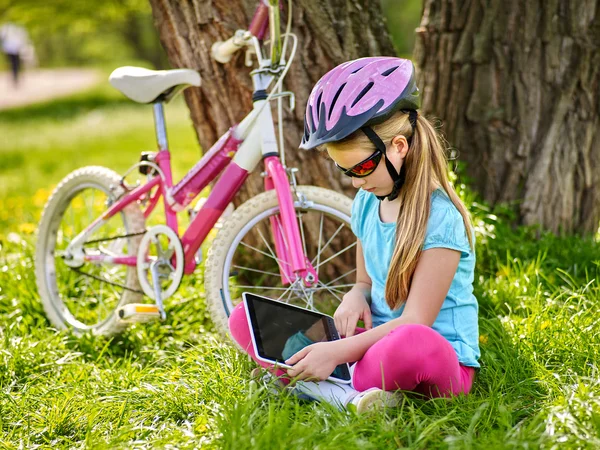 Ποδήλατα, ποδηλασία κοπέλα φορώντας κράνος στην ποδηλασία κάθεστε δίπλα στο ποδήλατο και να παρακολουθήσουν υπολογιστή tablet. — Φωτογραφία Αρχείου