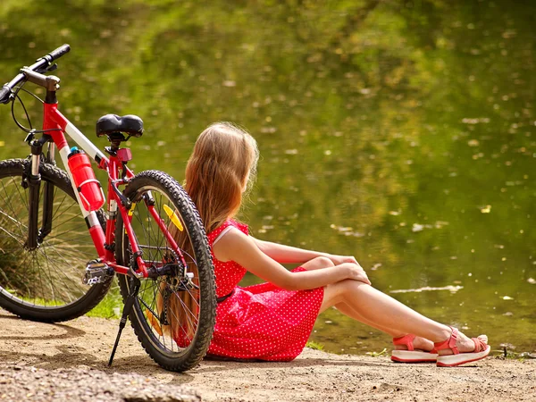 Fahrräder radeln Mädchen in Park. Mädchen sitzt angelehnt auf Fahrrad am Ufer. — Stockfoto