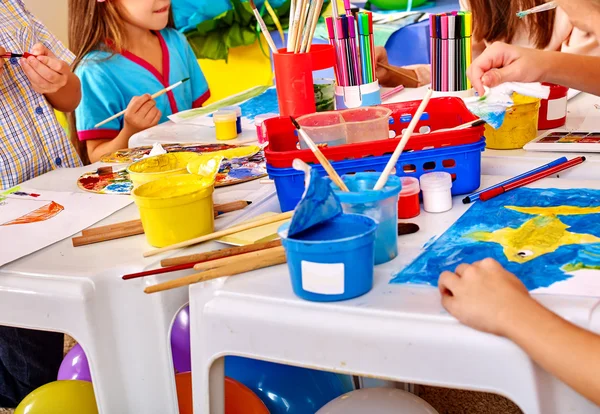 Niños con maestra pintando sobre papel en el jardín de infantes  . — Foto de Stock