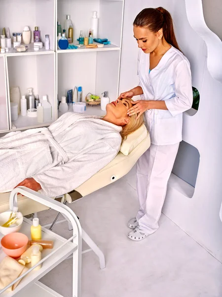 Жінка середнього віку приймає масаж обличчя в спа-салоні . — стокове фото