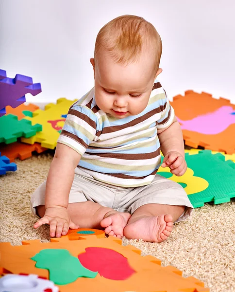 Kid chlapeček plavící se s puzzle hračky na podlaze. — Stock fotografie