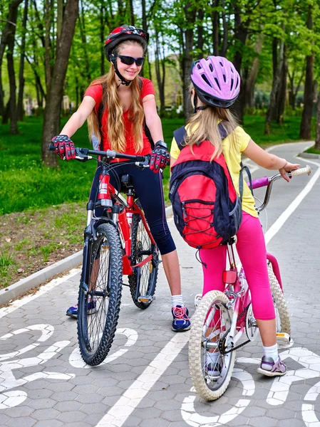 Girls children cycling on yellow bike lane.