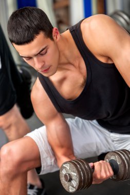 Kollarını dumbbells ile spor salonunda çalışan adam.