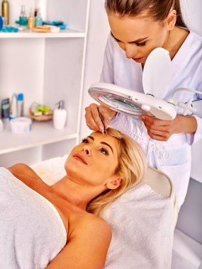 Spa salonda orta yaşlı kadın. Güzellik uzmanı tarafından tweezing kaş.