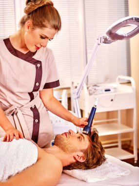 Genç adam elektrik yüz masajı alma.