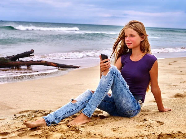 Girl on sand near sea call help by phone.